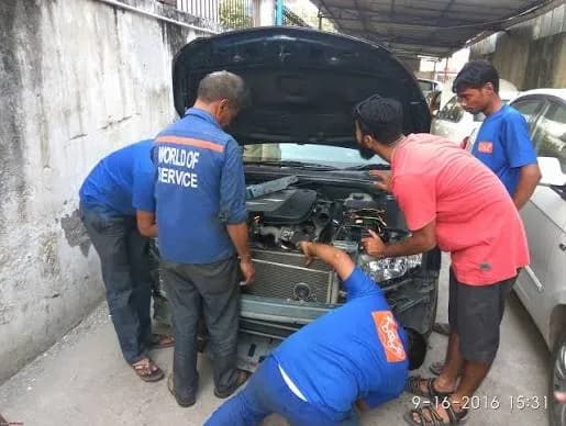 Collaborative team of 5 mechanics troubleshooting vehicle front bumper and radiator issues.
