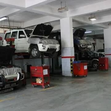 Mechanical repair bay showing multiple SUVs on post lifts with their hoods open.